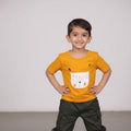 Child wearing a yellow shirt with a fox design and dark pants on a plain background
