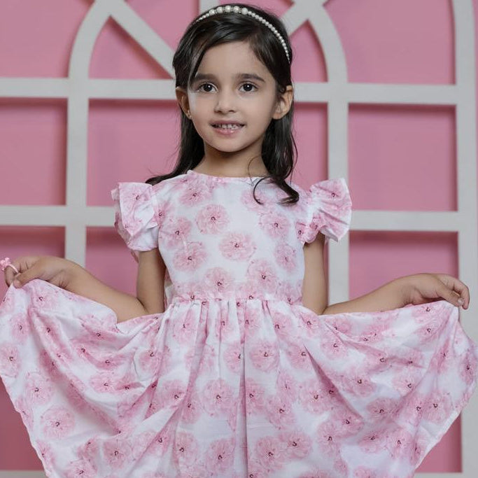 Young girl in a pink floral dress posing against a pink background
