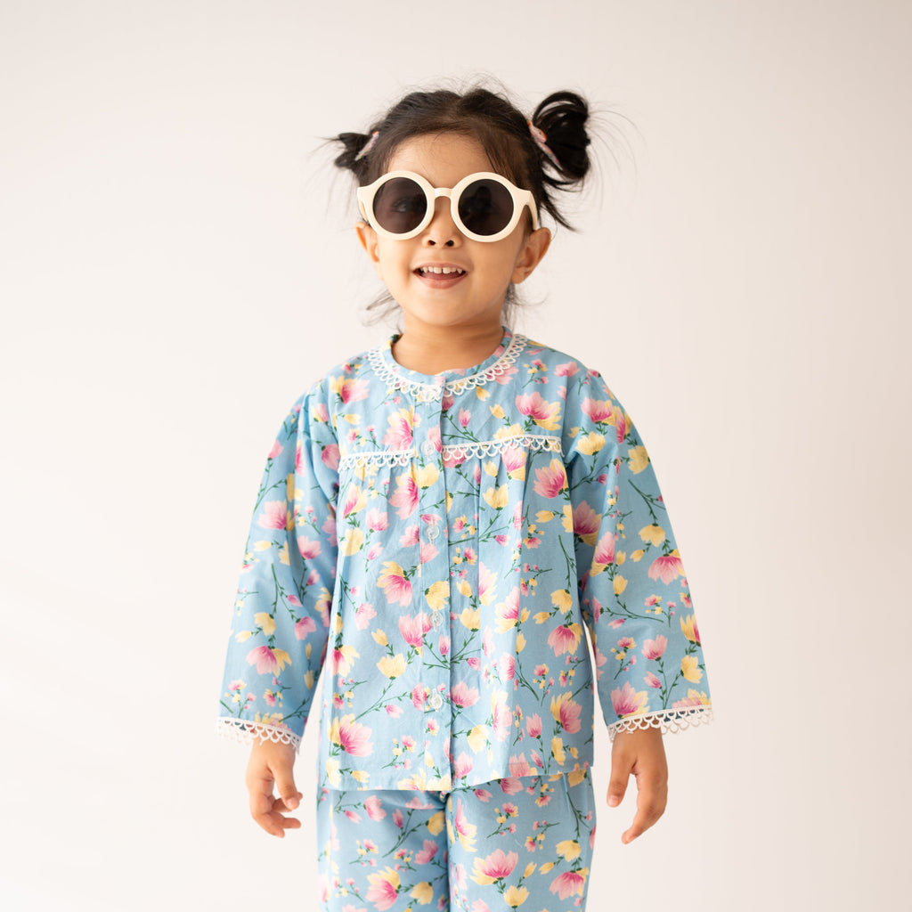 Child wearing a colorful pajama set with sunglasses on a white background