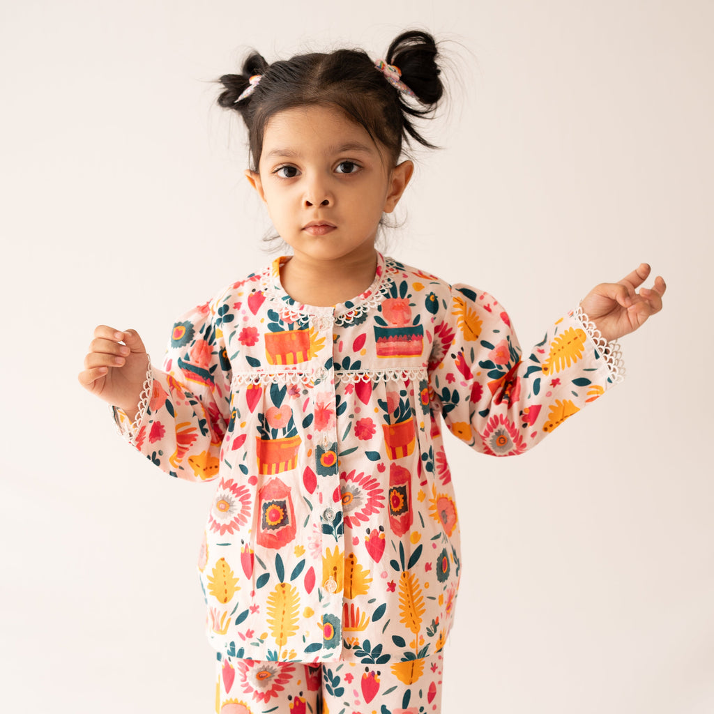 Child wearing a colorful pajama set with a floral and animal pattern on a white background