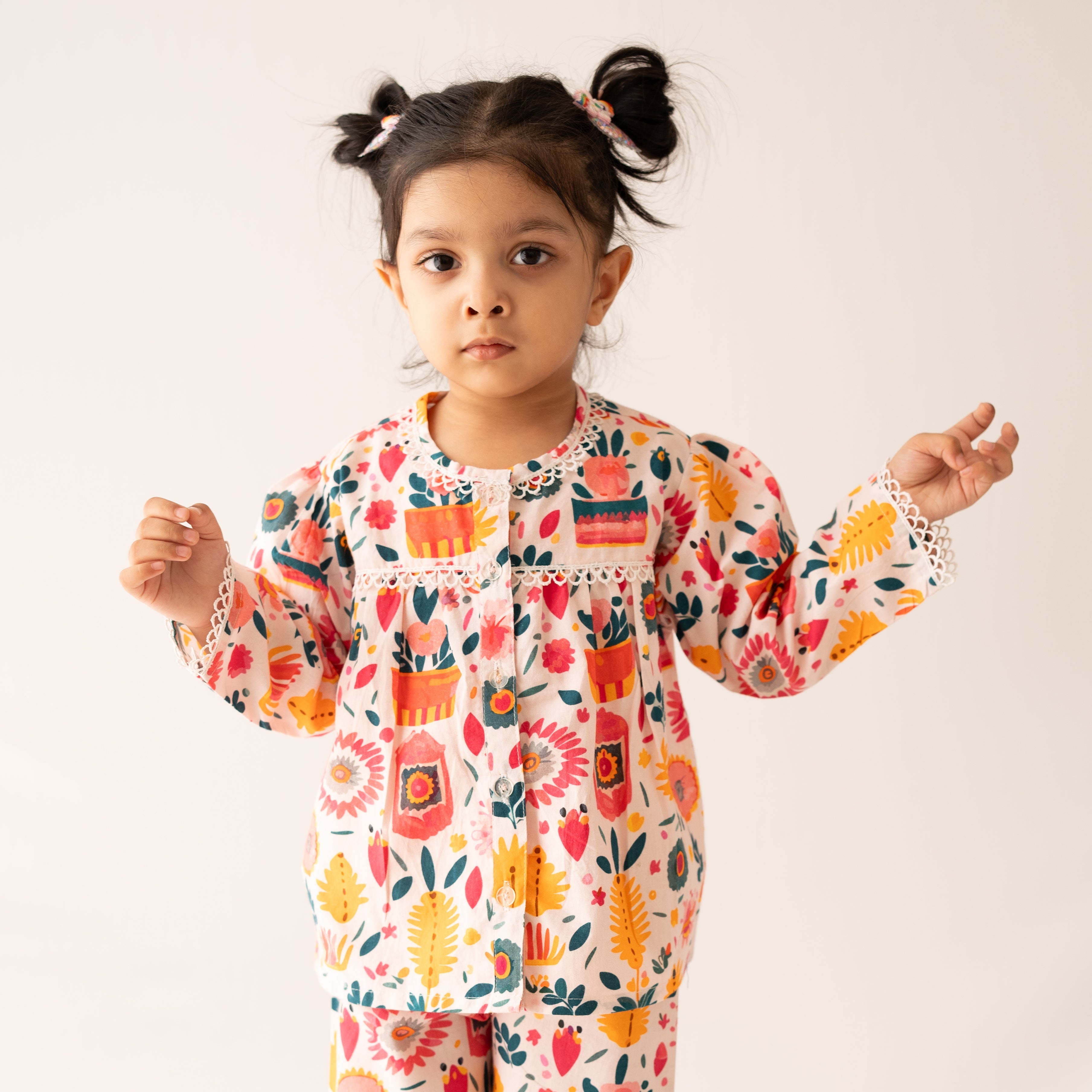 Child wearing a colorful pajama set with a floral and animal pattern on a white background