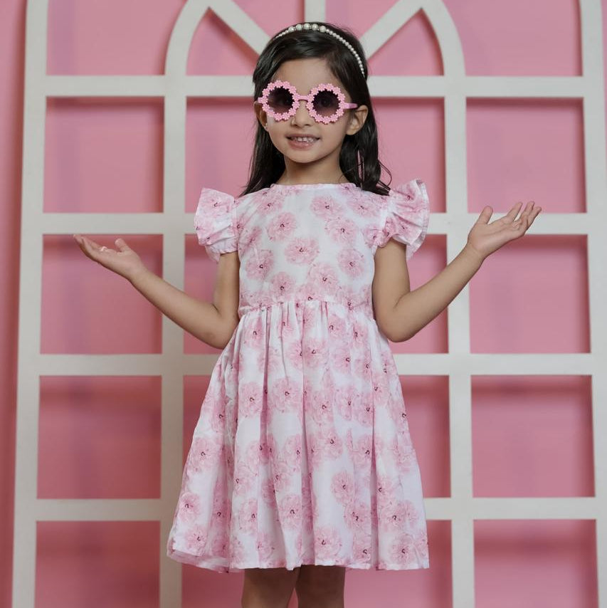 Young girl in a pink floral dress standing against a pink background